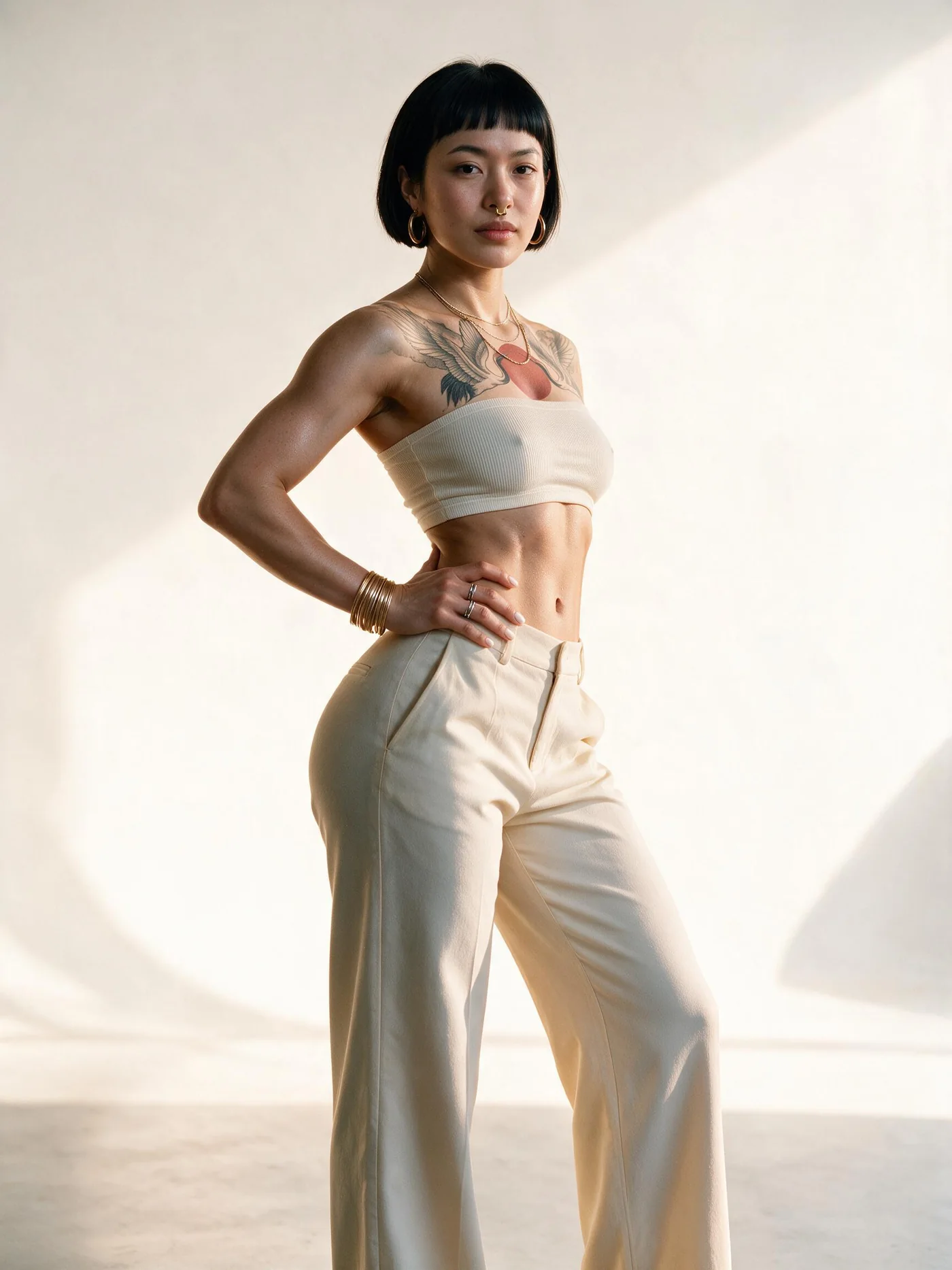 Sayumi Ueno em estúdio, top faixa e calça de alfaiataria creme, mão no quadril